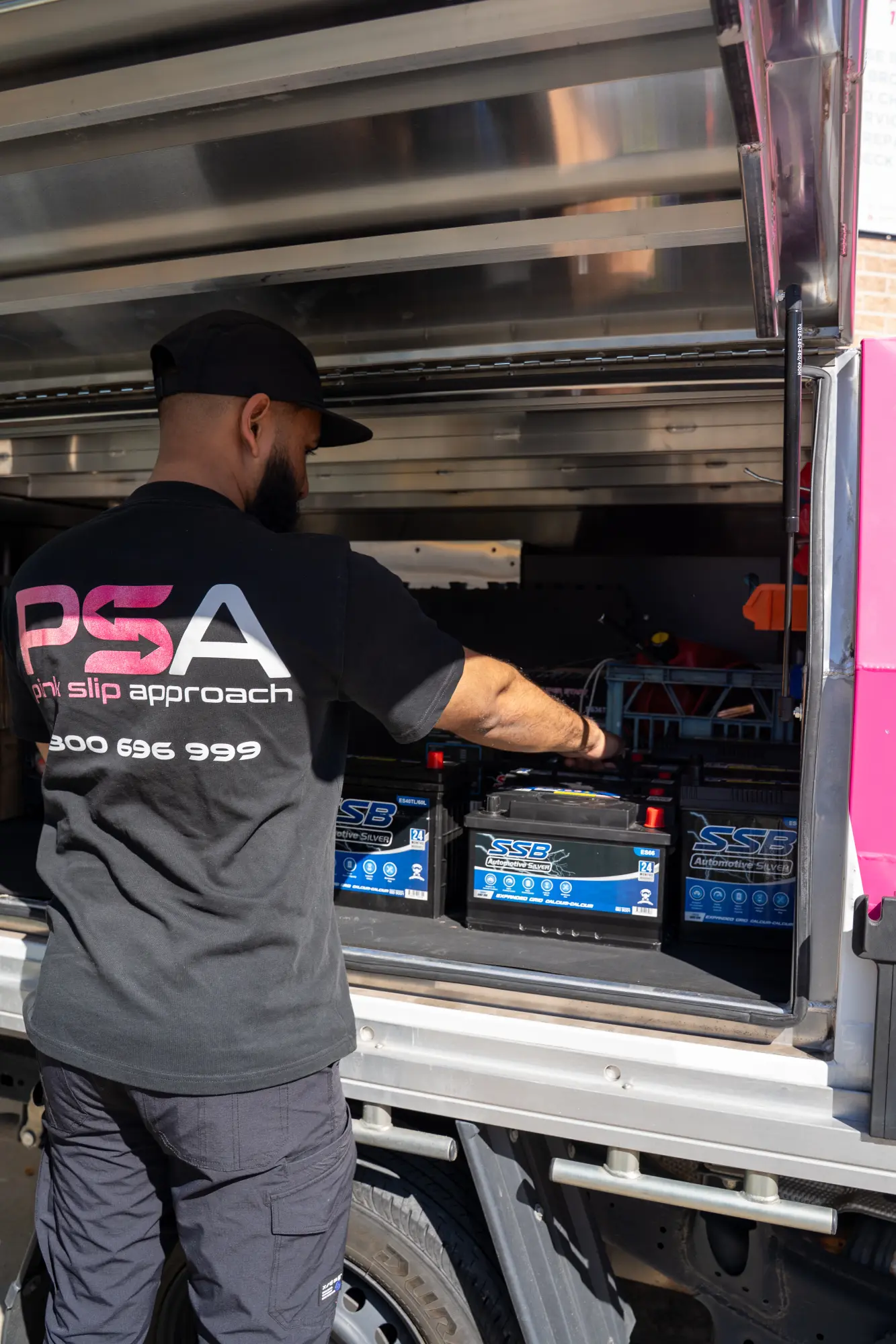A Pink Slip Approach technician lifting a car battery out of the ute’s canopy